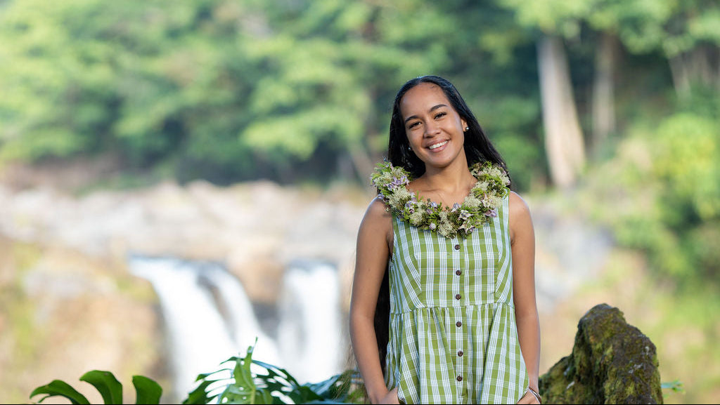 Model in green KAHUI Palaka with a waterfall in the background