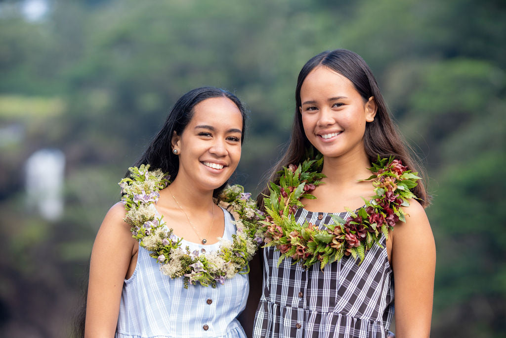 Two female models in KAHUI Palaka jumpsuits with lei around their necks
