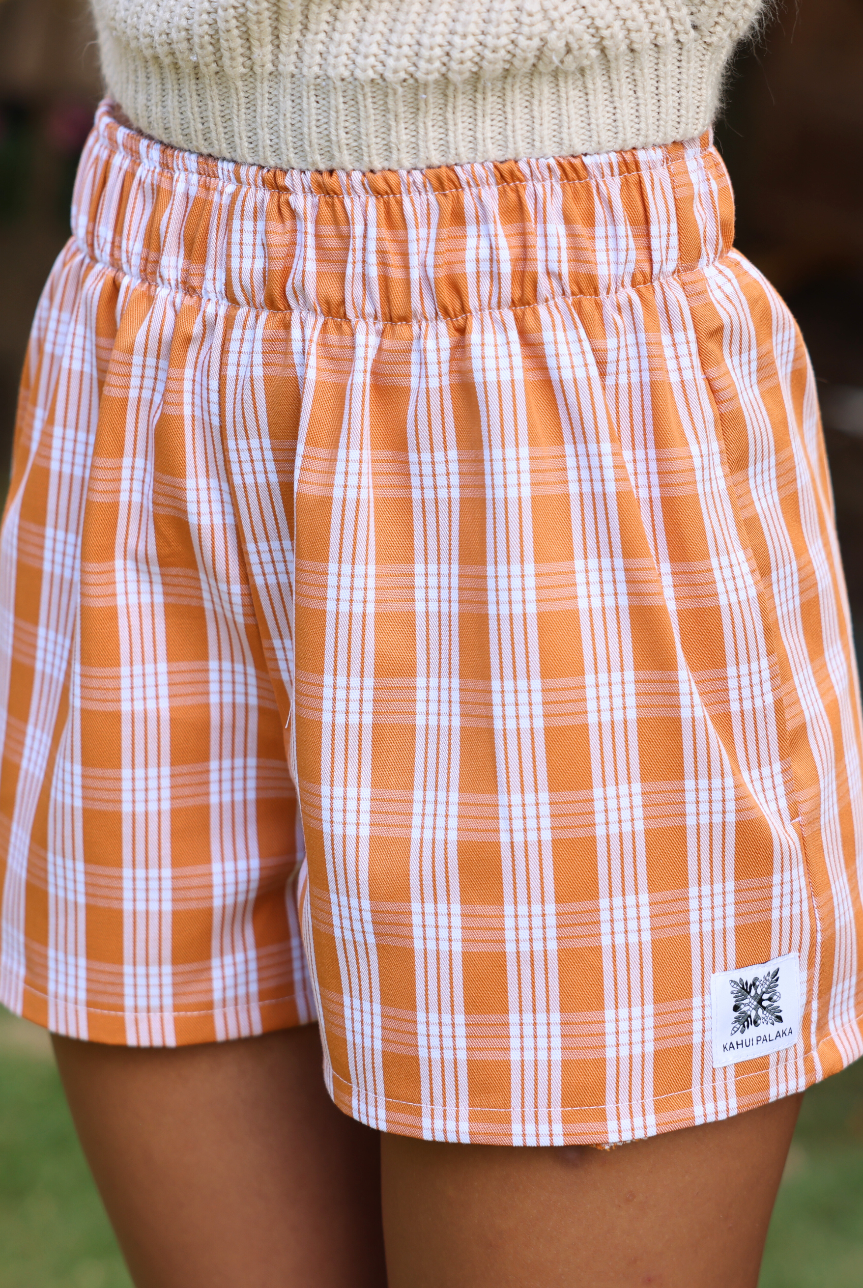 Wahine Holoholo Shorts 2.0 in Kaunaʻoa Rust showcase a Palaka print with an elastic waistband. The knit top adds cozy contrast.