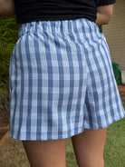 Wahine Holoholo Shorts 2.0 with a Palaka print, shown from the back. Elastic waistband, light blue tone, outdoors setting.